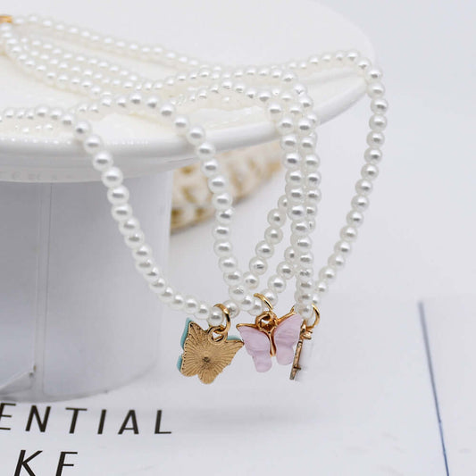 Elegant pearl bracelets with butterfly charms displayed on a stylish stand, perfect for adding charm to any outfit.
