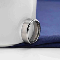 Brushed Wide Face 610mm Unisex Beveled Silver Titanium Ring on a blue cloth background with a white ceramic cup.