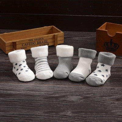 Newborn cotton children's socks terry socks displayed in a variety of patterns and colors on a wooden surface.