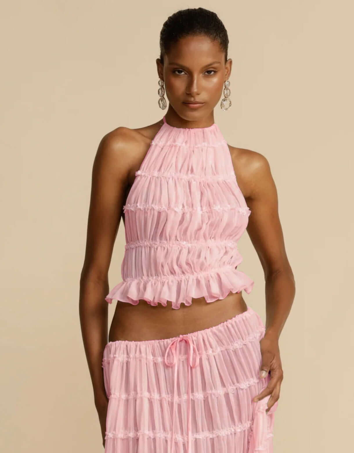 Model wearing a pink summer party dress with frills, perfect for warm weather events.