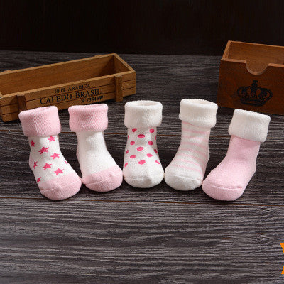 Newborn cotton children's socks terry socks in assorted colors and patterns arranged on a wooden surface.