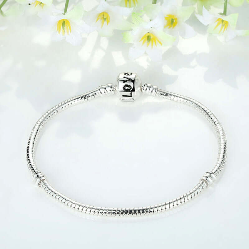 Silver beaded bracelet displayed among flowers, featuring a 'Love' charm, ideal for fashion jewellery and Christmas gifts.