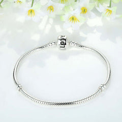 Silver beaded bracelet displayed among flowers, featuring a 'Love' charm, ideal for fashion jewellery and Christmas gifts.