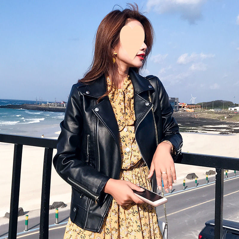 Woman wearing Baseball All Match Leather Jacket with a floral dress by the seaside.