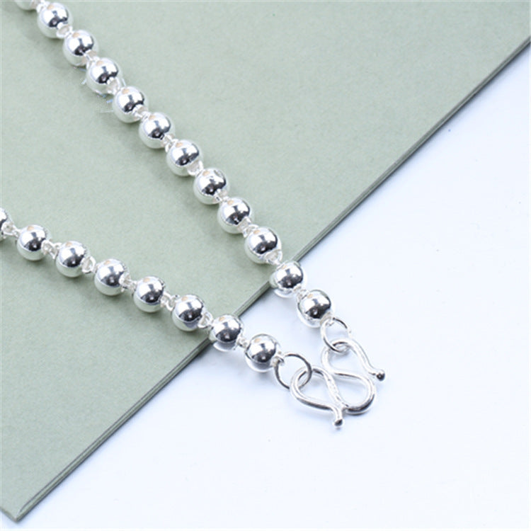 Round Beads Silver Bead Necklace laid on a soft background, showcasing its shiny geometric design and clasp.