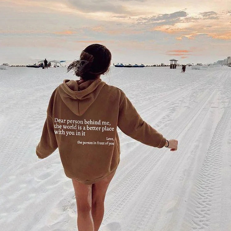 printed hoodie with pockets, a woman walking on the beach wearing a brown hoodie with a motivational quote printed on it.