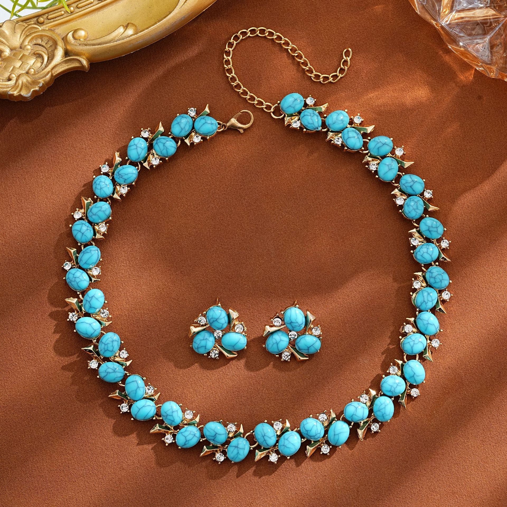Turquoise Pearl Necklace And Earrings Suite displayed on a brown background, featuring vibrant turquoise stones and rhinestones.