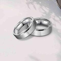 Brushed Wide Face 610mm Unisex Beveled Silver Titanium Ring displayed with a pair of stylish silver rings on a reflective surface.