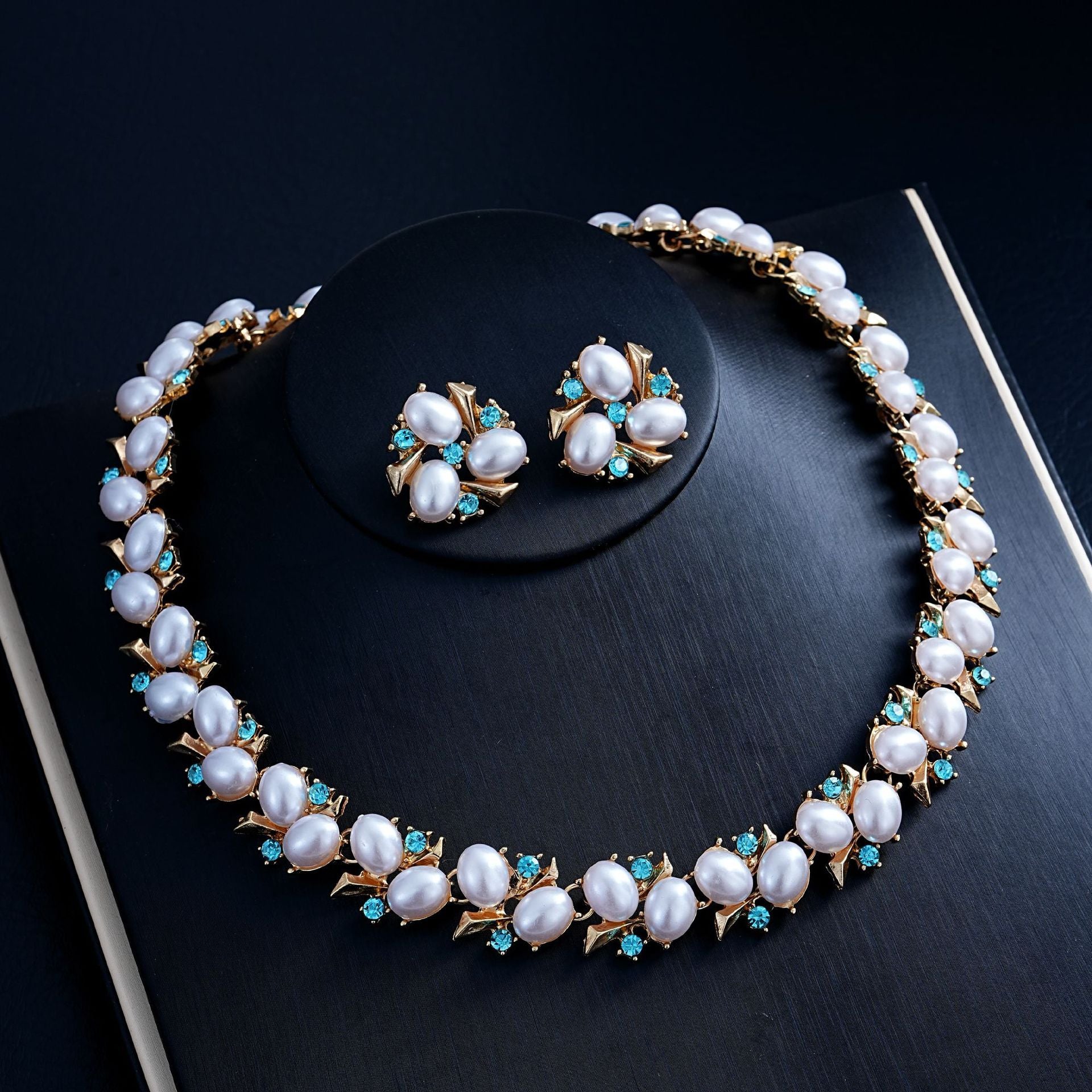 Turquoise Pearl Necklace And Earrings Suite displayed on a black surface, featuring rhinestone embellishments and electroplating.