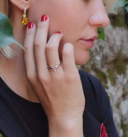 Close-up of a woman wearing the Sterling Silver Adjustable Butterfly Ring with stylish red nails and fashionable earrings.