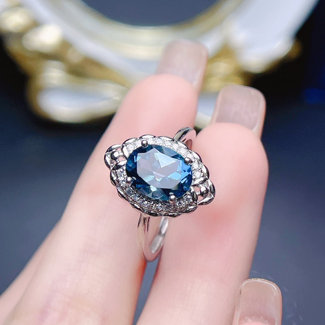Jewelry Natural Topaz Ring S925 Silver displayed on a finger with a polished silver design and a blue gemstone.